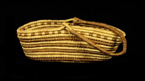 A fairly flat, open oblong basket with a single handle.